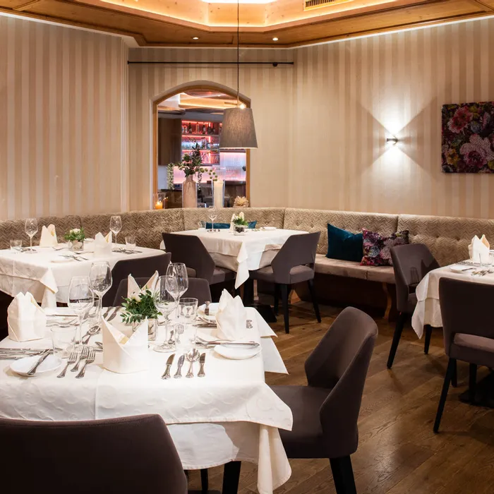 Ristorante elegante con tavoli apparecchiati, illuminazione moderna e angolo salotto accogliente